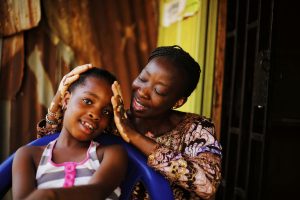 A heartwarming moment of a mother cradling her daughter outdoors in Abuja, Nigeria.